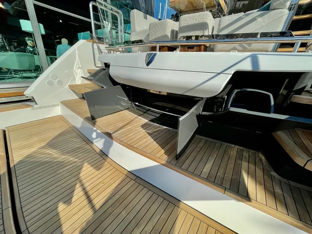 Stylish yacht interior featuring a wooden deck, plush seating, and open storage on the steps leading to the upper deck.